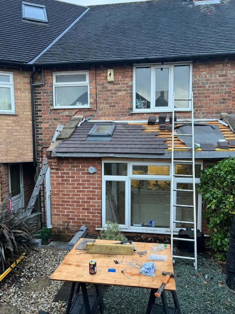 This is a photo of a roof extension that is having new roof tiles installed. This is a photo taken from the roof ridge looking down a tiled pitched roof on to a flat roof. Works carried out by Ely Roofing Repairs
