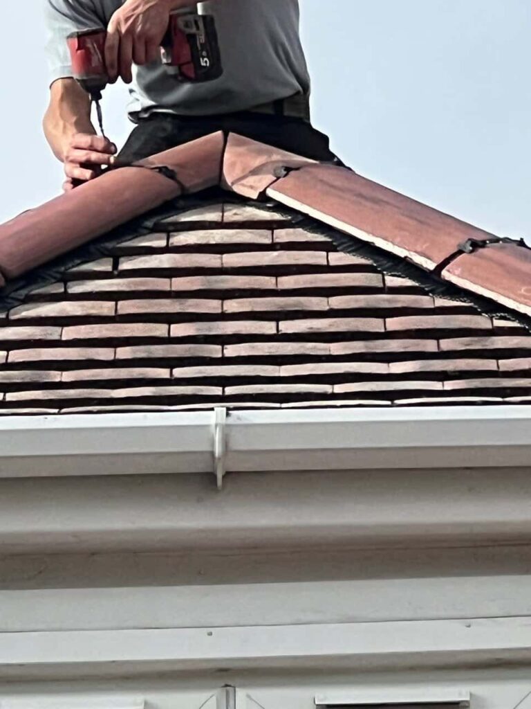 This is a photo of one of the operatives of Ely Roofing Repairs installing new ridge tiles